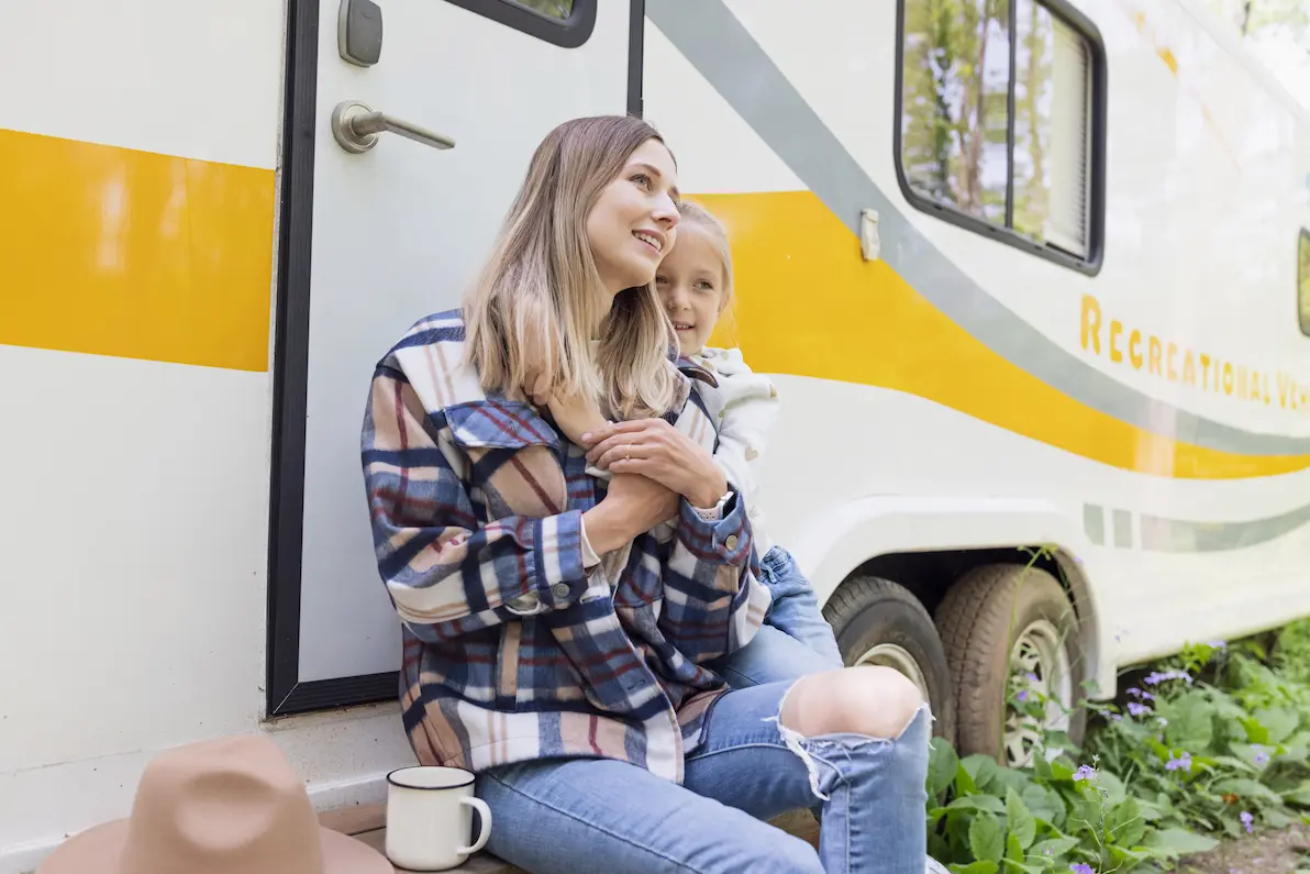 Happy mother and daughter sitting outside of an RV Happy mother and daughter sitting outside of an RV